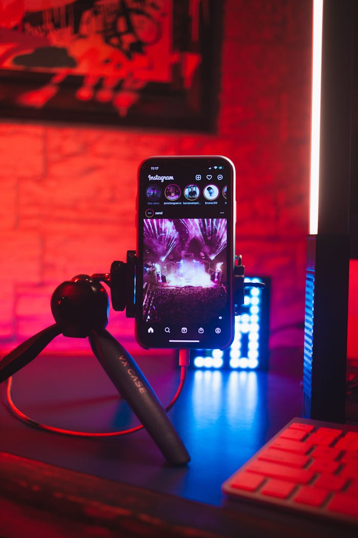 Smartphone on a tripod displaying Instagram, set against a vibrant neon red and blue backdrop.