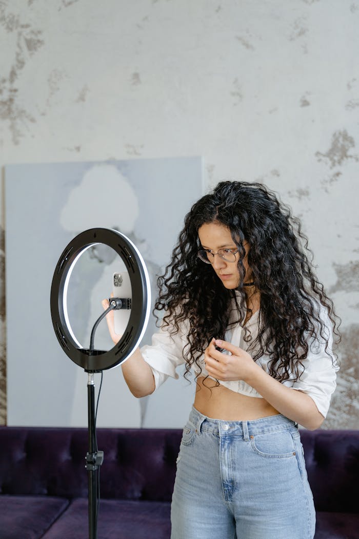 our-services-02 Young woman adjusting a ring light indoors, perfect for vlogging and content creation.