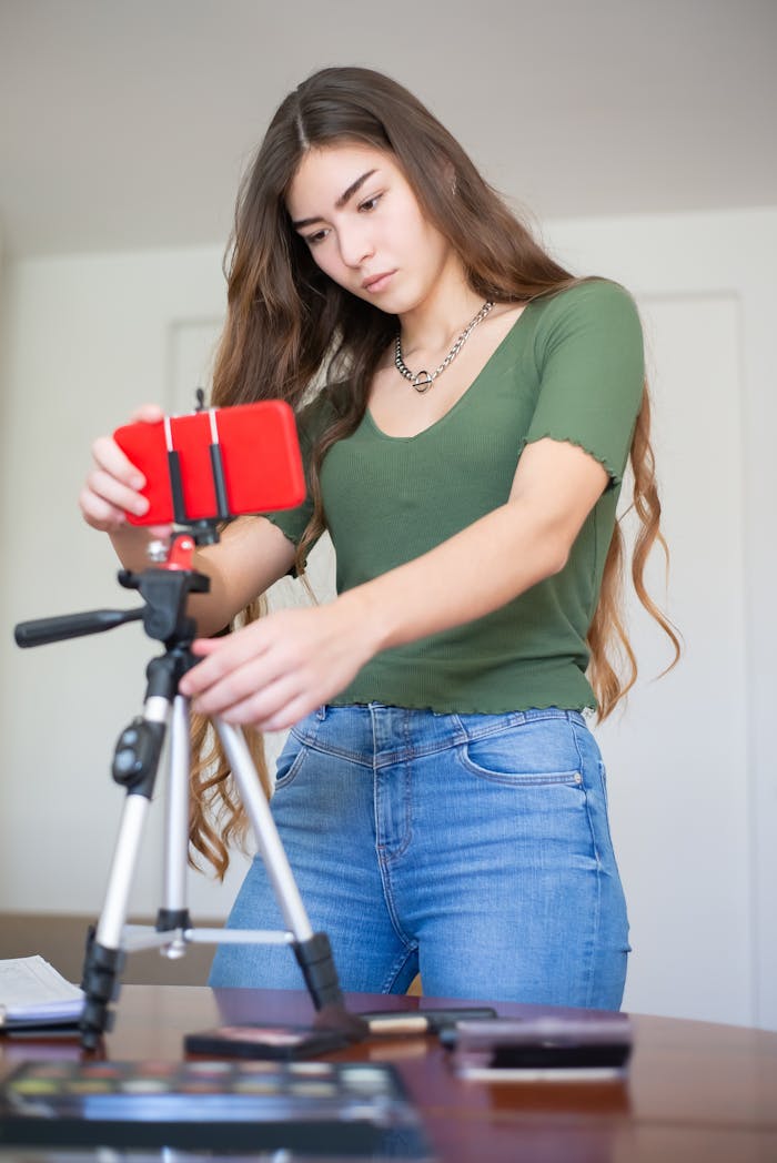Young woman adjusting a mobile tripod indoors for vlogging.