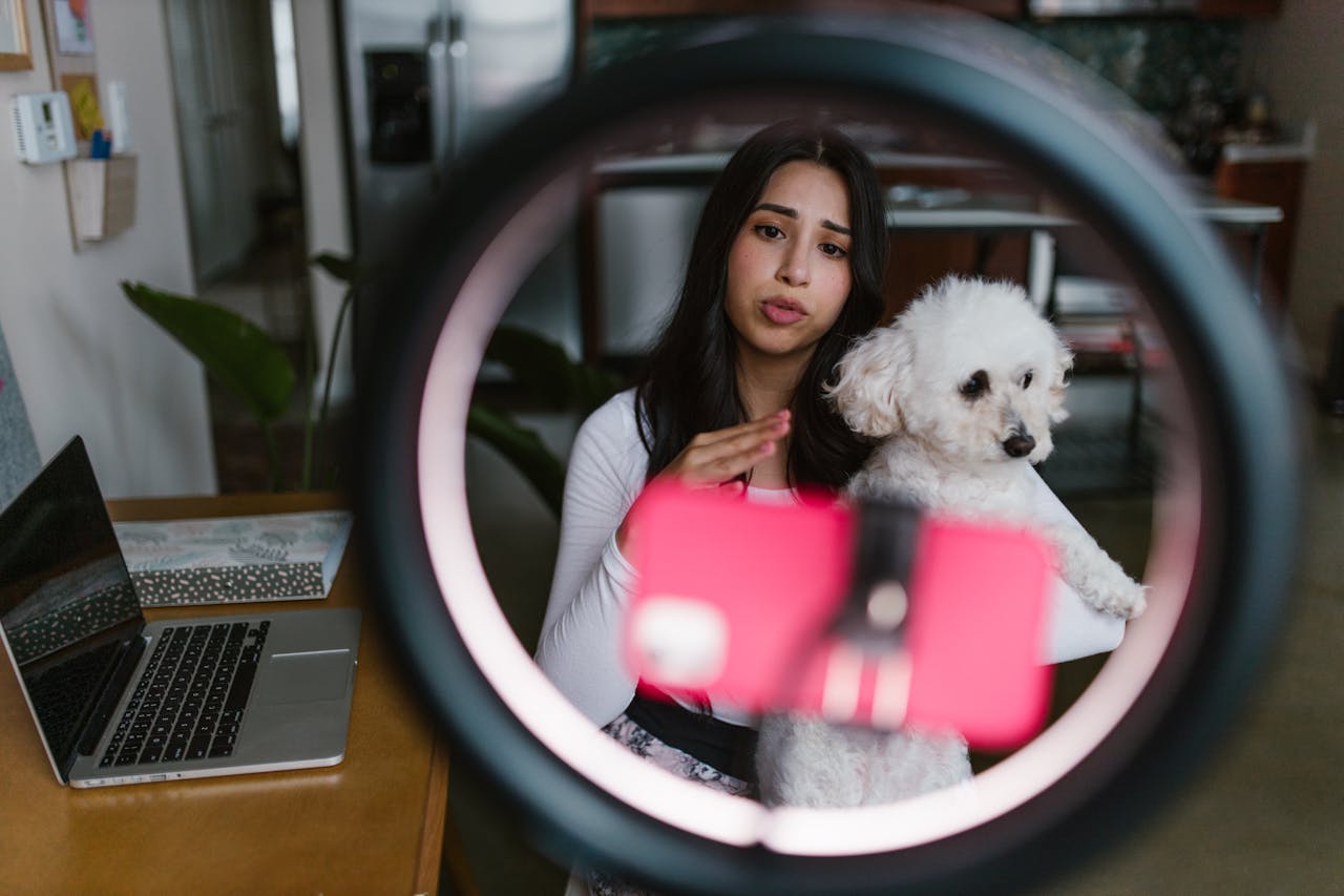 our-services-03 Young woman vlogging with her dog at home, creating content indoors.